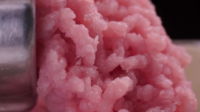Cooking minced meat with a manual meat grinder. Close-up of front part of mincing-machine with mincemeat in. Showing the forcemeat process.