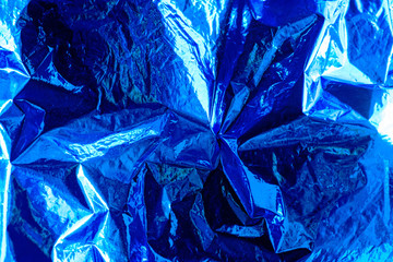 Bright christmas and new year blue background. Shiny blue foil texture.