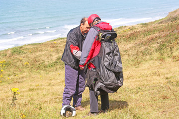 Tandem paraglider preparing passenger