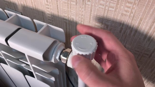 Regulation of the heating battery in the room. Human turns the temperature control valve to increase. Close-up