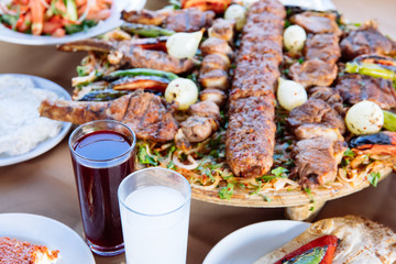 Traditional Turkish Adana kebab or kebap meat food, appetizers, raki and salgam on table from top view in turkish restaurant.	
