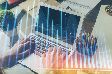 Double exposure of businessman's hands with laptop and stock market graph background. Concept of...