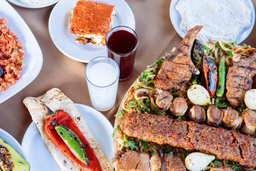 Traditional Turkish Adana kebab or kebap meat food, appetizers, raki and salgam on table from top view in turkish restaurant.	