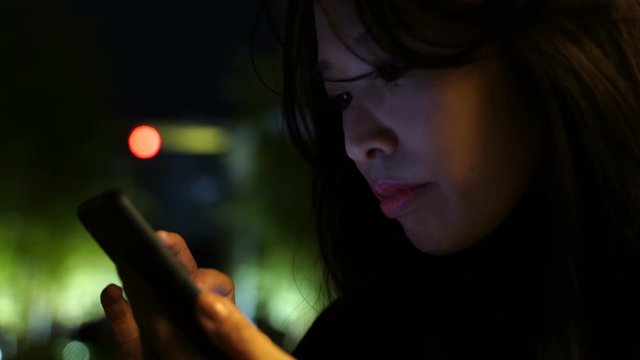 スマートフォンを見る女性　夜