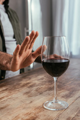 Cropped view of alcohol addicted man pulling hand to wine glass