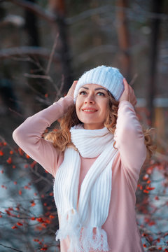 Winter portrait of young beautiful brunette woman wearing white snood in snow. Snowing winter beauty fashion concept.