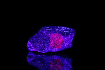 macro mineral stone ruby under ultraviolet light on a black background