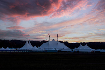 Circus tent under a warn sunset and chaotic sky without the name of the circus company which is...