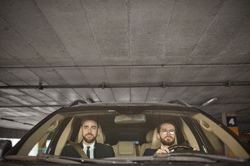Two young businessmen sitting in the car together in the parking they are going in business trip