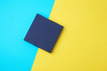 closed dark blue paper cardboard box on a yellow-blue background