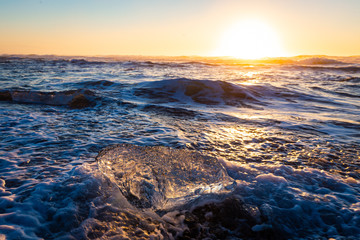 Iceberg melting at sunrise on black volcano beach of Jökulsárlón glacier lagoon, Iceland