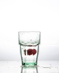 A glass of clean water and fresh red strawberries