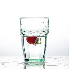 A glass of clean water and fresh red strawberries