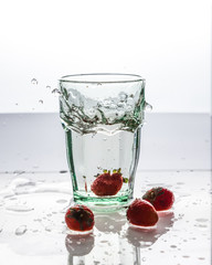 A glass of clean water and fresh red strawberries