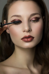 Close-up of female green eye with brown thick eyeliner. brown brush colors extra long eyelashes. Thick beautiful eyebrows and natural lips. Clean smooth skin. Cosmetology and spa. dark lips