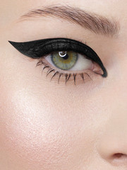 Glamour close-up portrait of beautiful woman model face with winged black eyeliner make-up, clean skin on white background. Long eyelashes and thick eyebrows. - obrazy, fototapety, plakaty