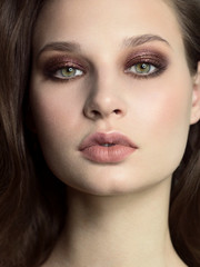 Beautiful brunet model woman face with green eyes and perfect make-up. Portrait of beauty young brunet girl with natural lips and smoky eyes, thick eyesbrow . Female face with clear skin close-up.