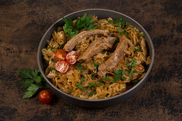 Bigos of stewed sauerkraut with pork ribs. Traditionally the Polish dish in a plate decorated with greens and tomatoes stands on a wooden table.