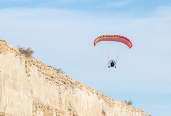 Fototapeta na wymiar Athletes on a motorized parachute fly over the ruins of the Roman aqueduct near Caesarea city in northern Israel