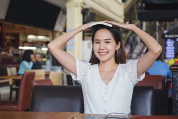 Close up beautiful smiling asian woman in a white dress a book on over head and put her hands on a...