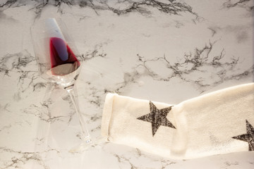 Sleeve of white sweater holds glass of red wine on marble table, top view, copy space