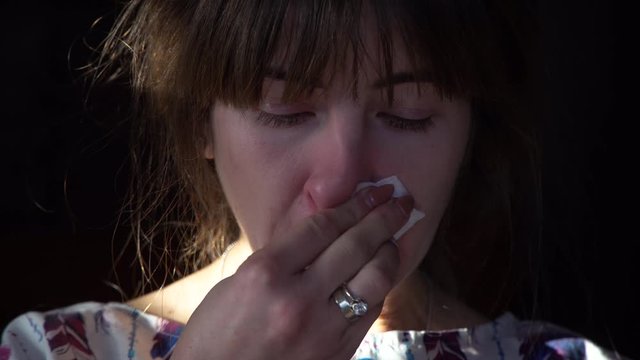 The girl blows snot into her nose. Fainting, red nose, poor health. Viral disease.Close up