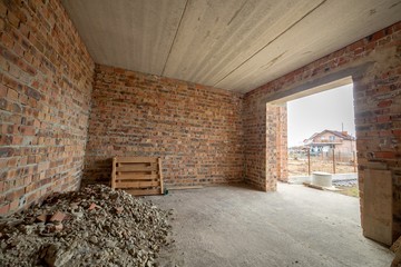 Interior of unfinished brick house with concrete floor and bare walls ready for plastering under construction. Real estate development