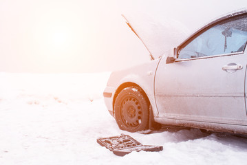 A set of automotive tools next to a car in winter. The concept of low-quality diesel fuel, the...