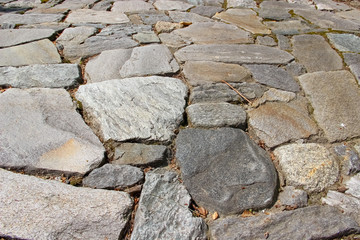 An old pavement cobbled with natural rocks. Photo in perspective 