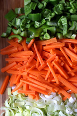 Chopped carrots, leek and green peppers on a cutting board. Top view.