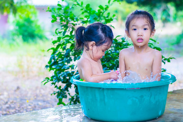 Two Asian girls kindergartens are having fun playing in the water bath.