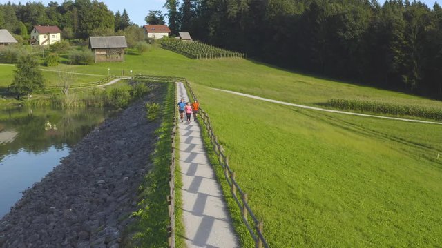 Aerial drone footage of three runners running by the lake enjoying in beautiful day and nature
