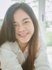 Happiness concept from Close up portrait of cheerful young Asian woman smiling with braces teeth and relaxing in coffee shop.