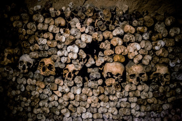 Skulls and bones in Paris catacombs, France. Old broken skull placed on the bones. Underground...
