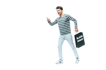 emotional man pointing and holding shopping bag on black friday, isolated on white
