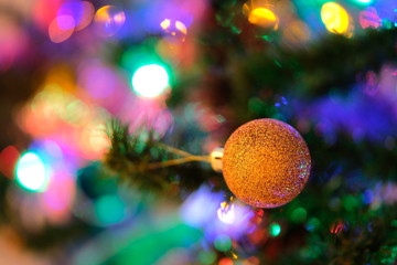 Orange Christmas ball decoration on a Christmas tree with intense blurry background or bokeh