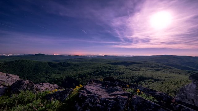 Night panorama with moon rising above the landscape and clouds envelop him 4K Time Lapse