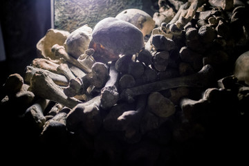 Skulls and bones in Paris catacombs, France. Old broken skull placed on the bones. Underground cemetery.