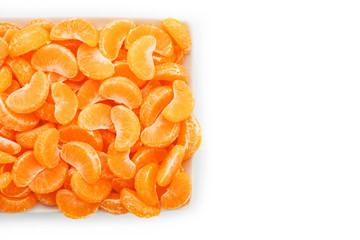 Slices of juicy tangerines in a white plate on a white background.