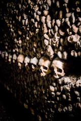 Skulls and bones in Paris catacombs, France. Old broken skull placed on the bones. Underground cemetery.