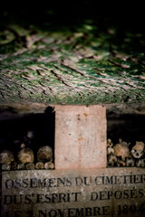 Skulls and bones in Paris catacombs, France. Old broken skull placed on the bones. Underground cemetery.