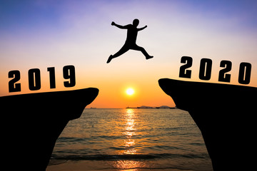 Silhouette young man jumping from 2019 to 2020 years