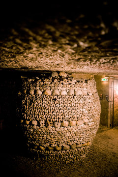 Skulls and bones in Paris catacombs, France. Old broken skull placed on the bones. Underground cemetery.