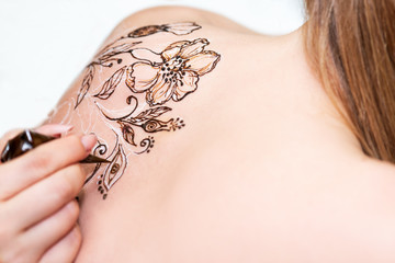 Drawing process of henna mehndi ornament on womans back