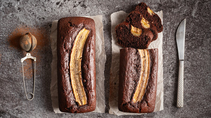 Two chocolate banana loafs on a gray stone background