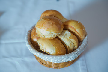 a basket from dough . Sweet buns with poppy seeds in a wicker basket, around rye bread with sesame seeds .