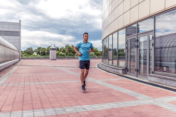 Fototapeta na wymiar male athlete runs in morning on run, in motion, workout training, in summer in the city. Fitness motivation youth lifestyle. Free space for copy text.
