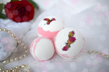 Obraz na płótnie Canvas Bath bombs, towel, pearl and red rose on white background. Romantic spa wellness concept. Valentines day, Mothers day or wedding celebration closeup composition