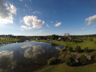 Fototapeta na wymiar Large pond, barns, blue sky and green grass as seen from an aerial drone