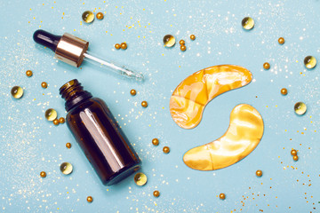 Face serum, golden eye patches and vitamin capsules. Collagen, hyaluronic acid for skin care. Achievements of modern science in cosmetic to preserve beauty. Flat lay. Trendy colors